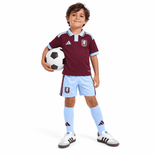 49d625c6-2d37-4fba-b929-14c0ce65a9b6 - UAE SPORT STORE Child in Aston Villa home kids kit 2026/27 holding soccer ball.