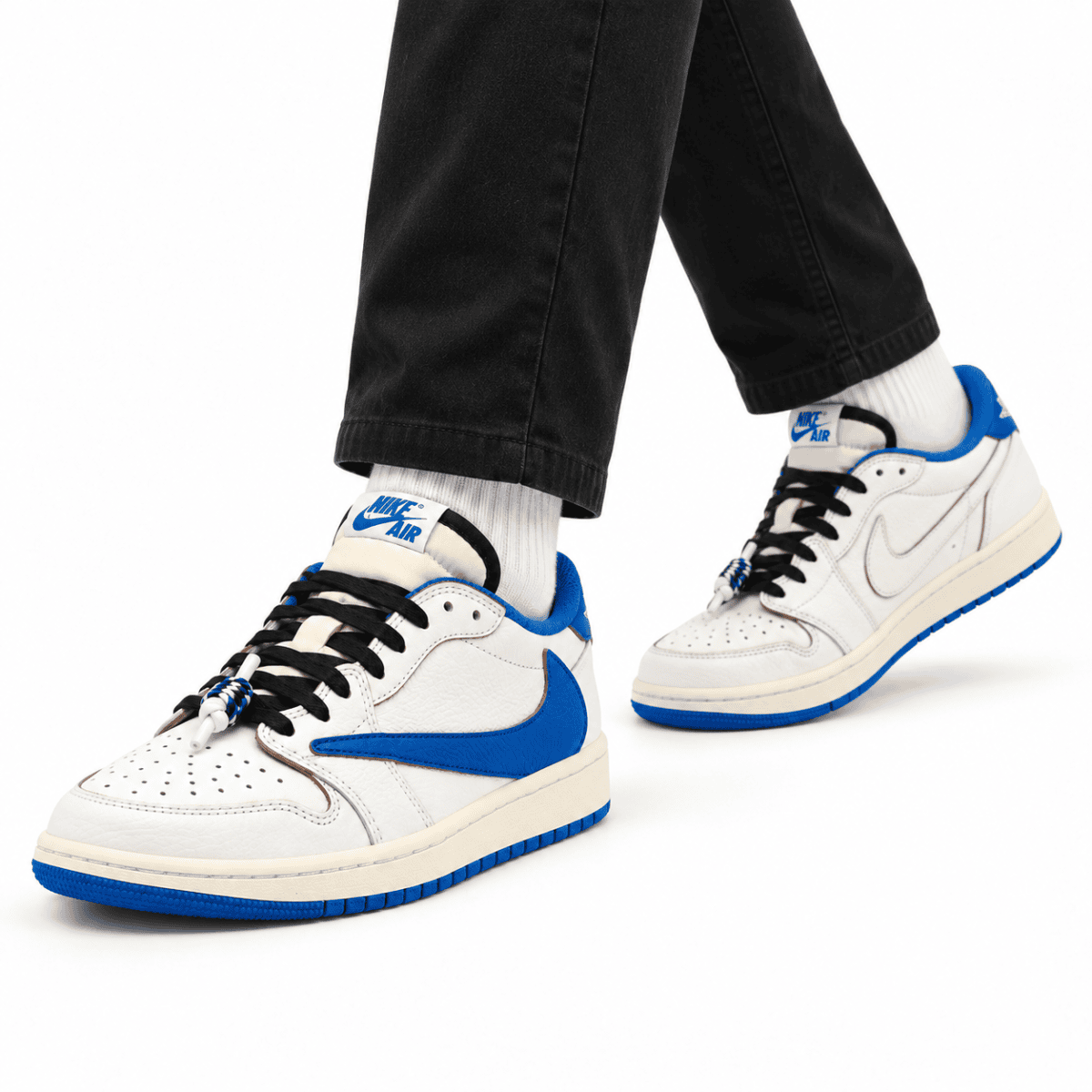 White and blue Nike Air Jordan 1 Low OG sneakers on black pants and white socks.