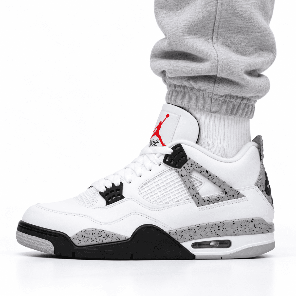 Close-up of a person wearing white Air Jordan 4 Retro OG sneakers with black and grey accents.