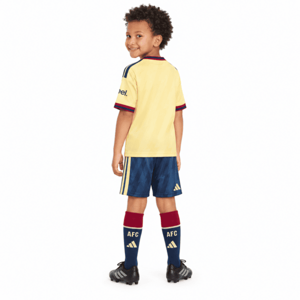 Child wearing Arsenal third kids kit 2026/27 with yellow jersey and blue shorts.