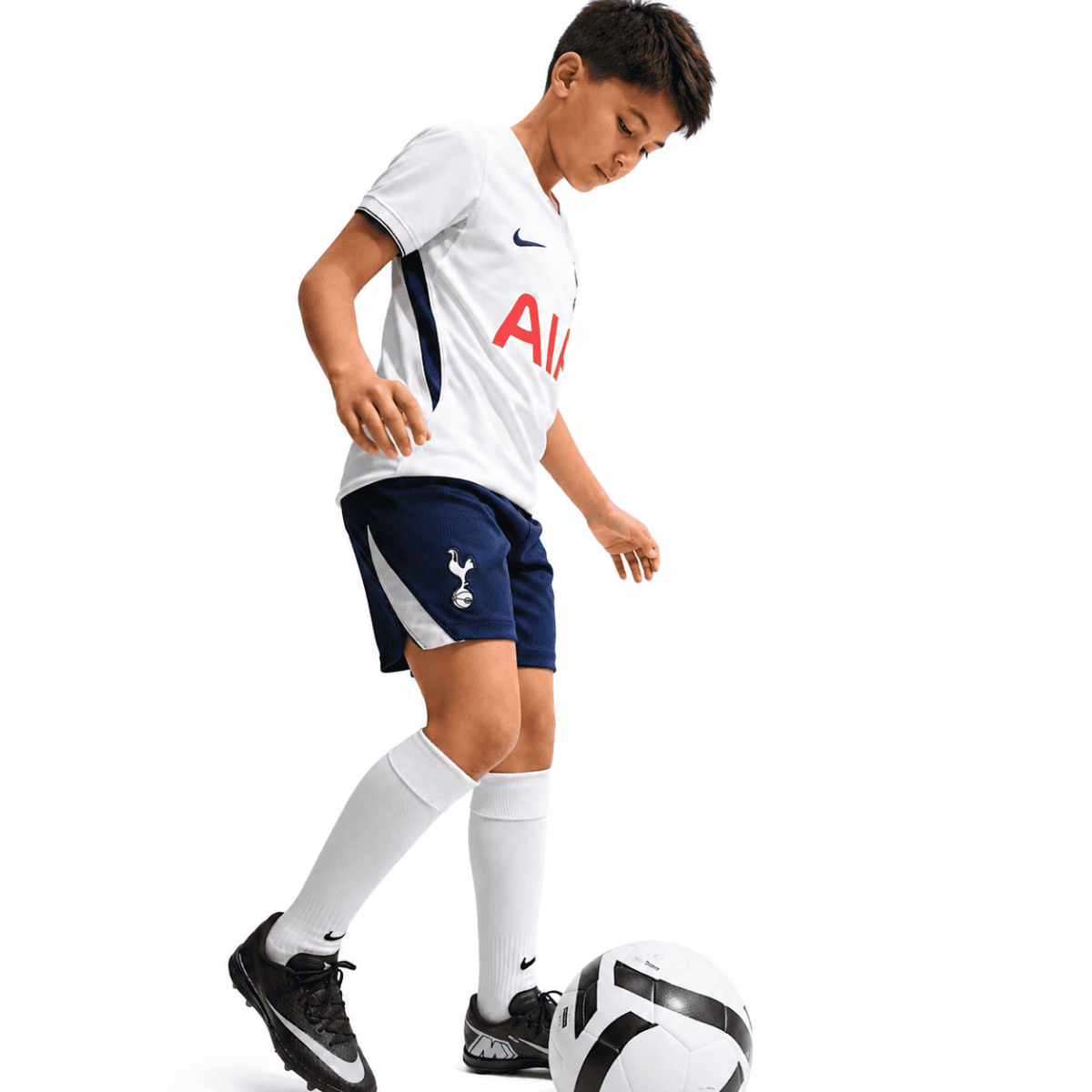 Kids Tottenham home kit 2026/27 with white shirt and navy shorts, playing with a soccer ball.