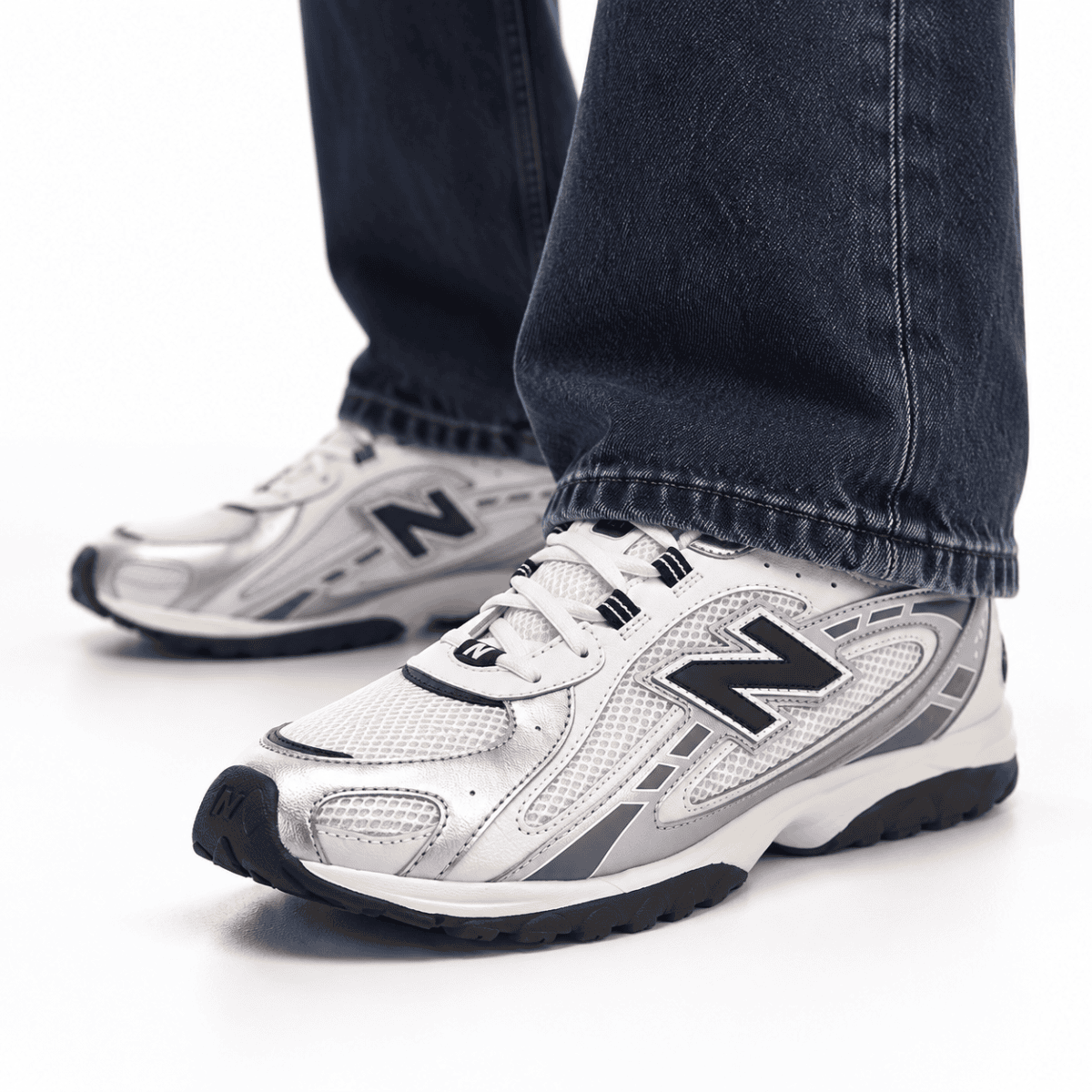 Person wearing white and silver New Balance 204L trainers with black accents.