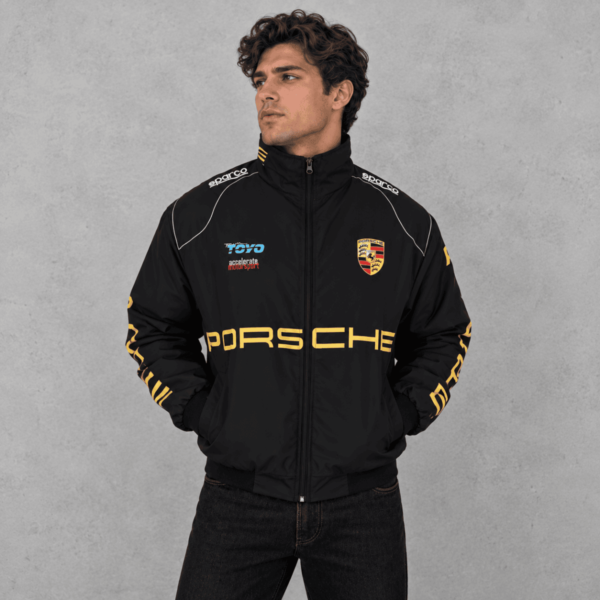 Black Porsche racing jacket with logo and yellow accents, front view.