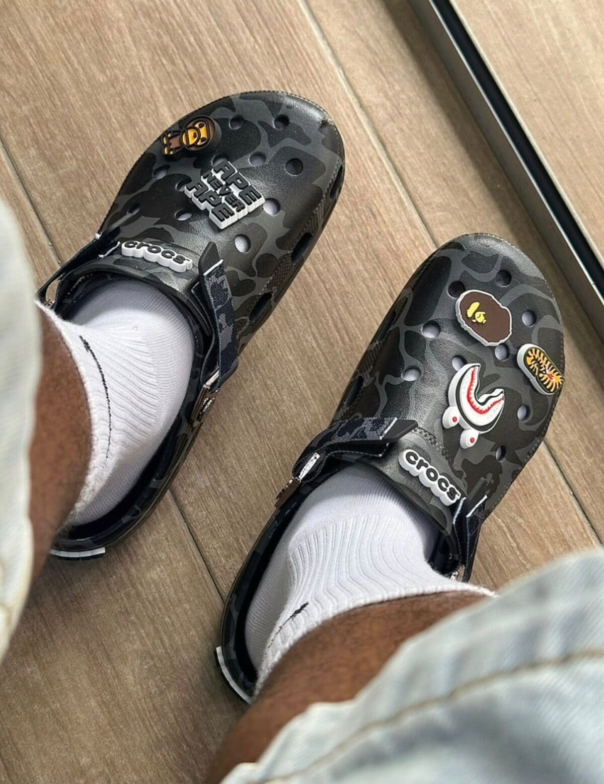 Pair of BAPE x Crocs Classic Clog with black camouflage pattern and patches.