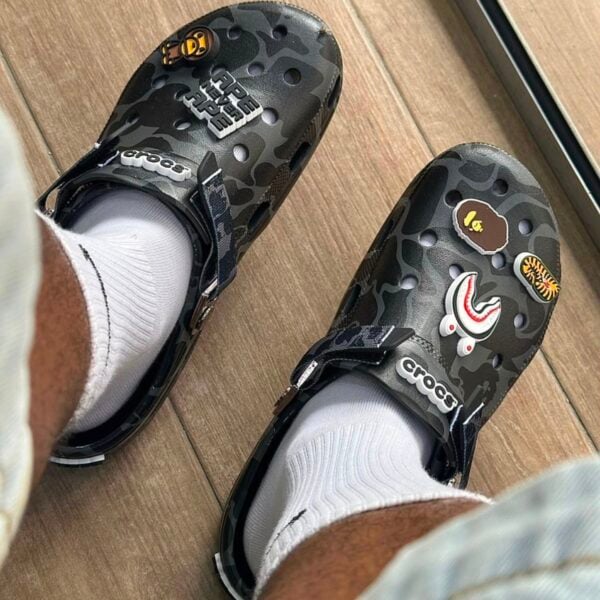 789a0549-1864-47a1-a519-89e96e14a41f - UAE SPORT STORE Pair of BAPE x Crocs Classic Clog with black camouflage pattern and patches.