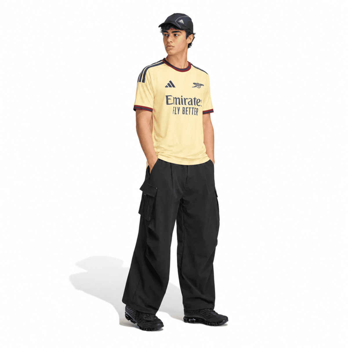Young man in Arsenal third jersey 2026/27, beige with maroon accents, black pants.