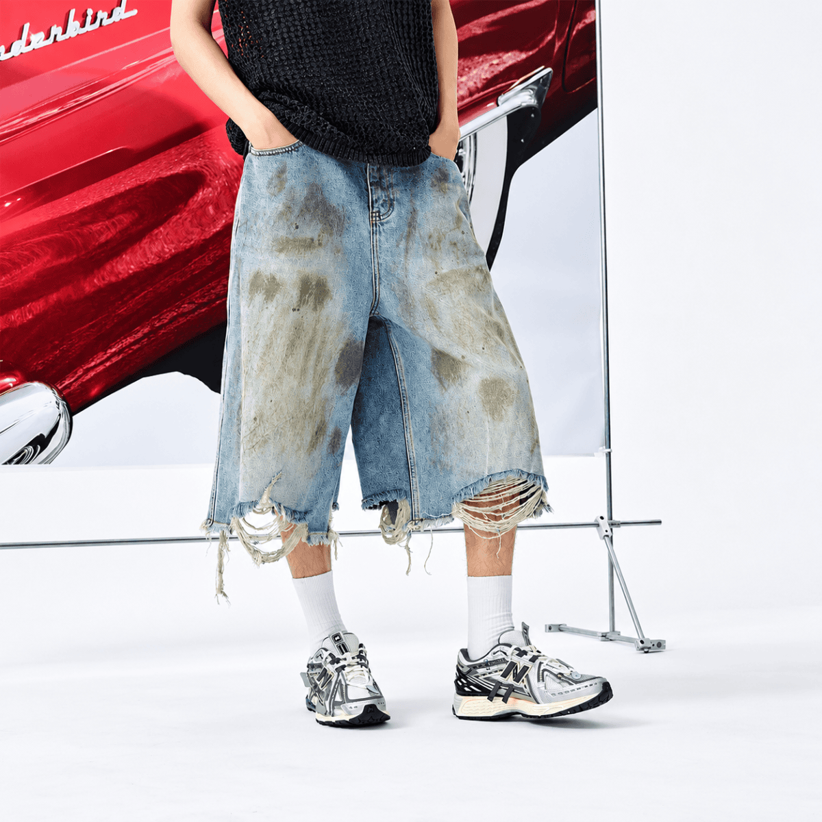 Person wearing distressed denim shorts, white socks, and New Balance sneakers.