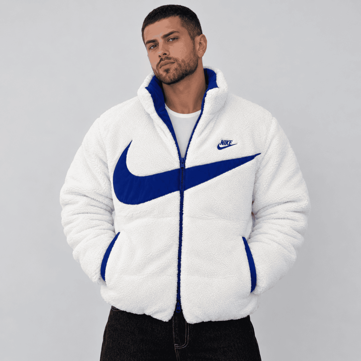 Man wearing white Nike fleece jacket with blue logo and accents.
