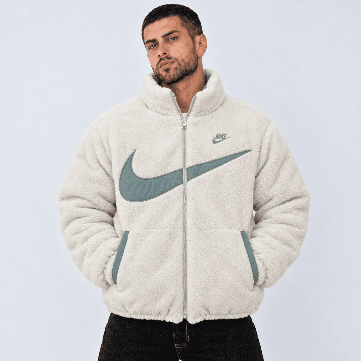 Man wearing a cream Nike fleece jacket with large logo on front.
