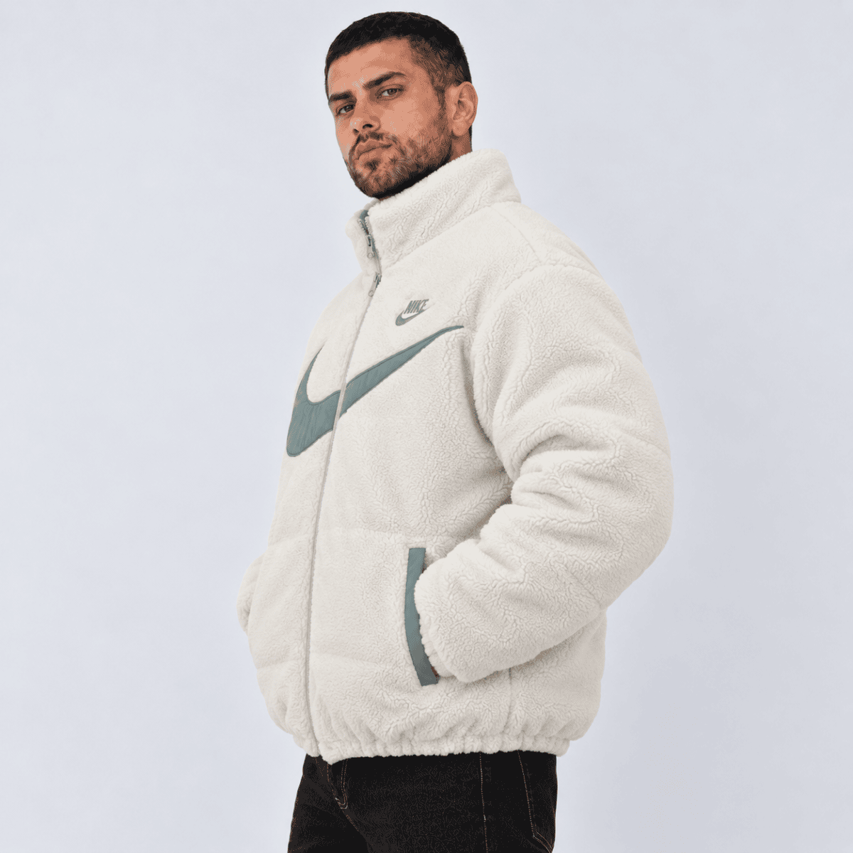 Man wearing a white Nike fleece jacket with large logo on front.