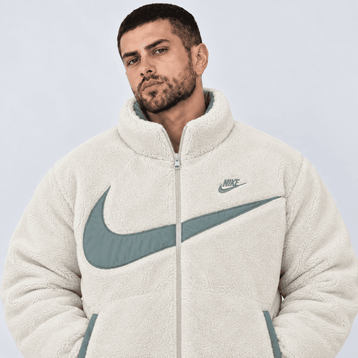 Man wearing a cream Nike fleece jacket with large Nike swoosh logo.