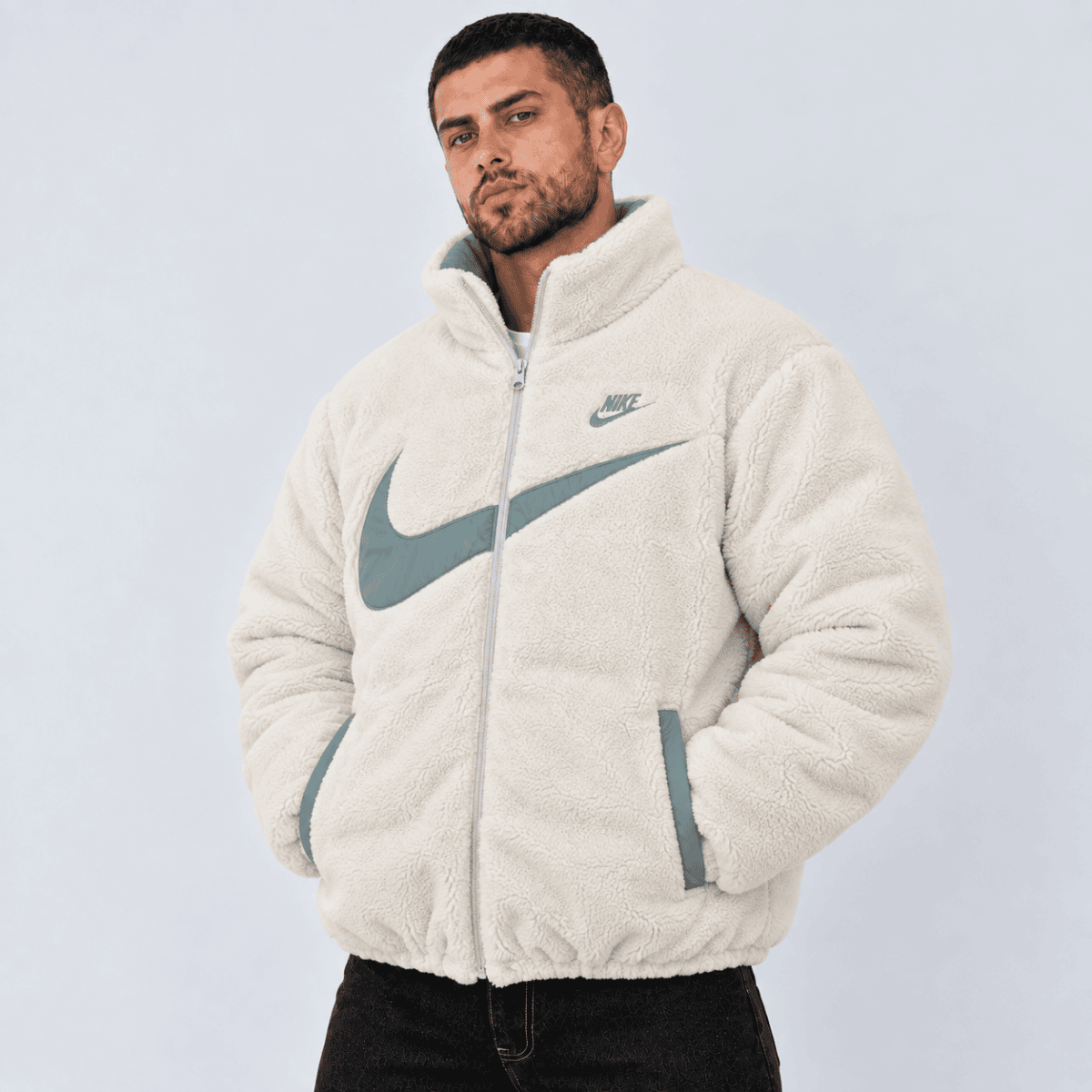 Man wearing a cream Nike fleece jacket with large logo on front.