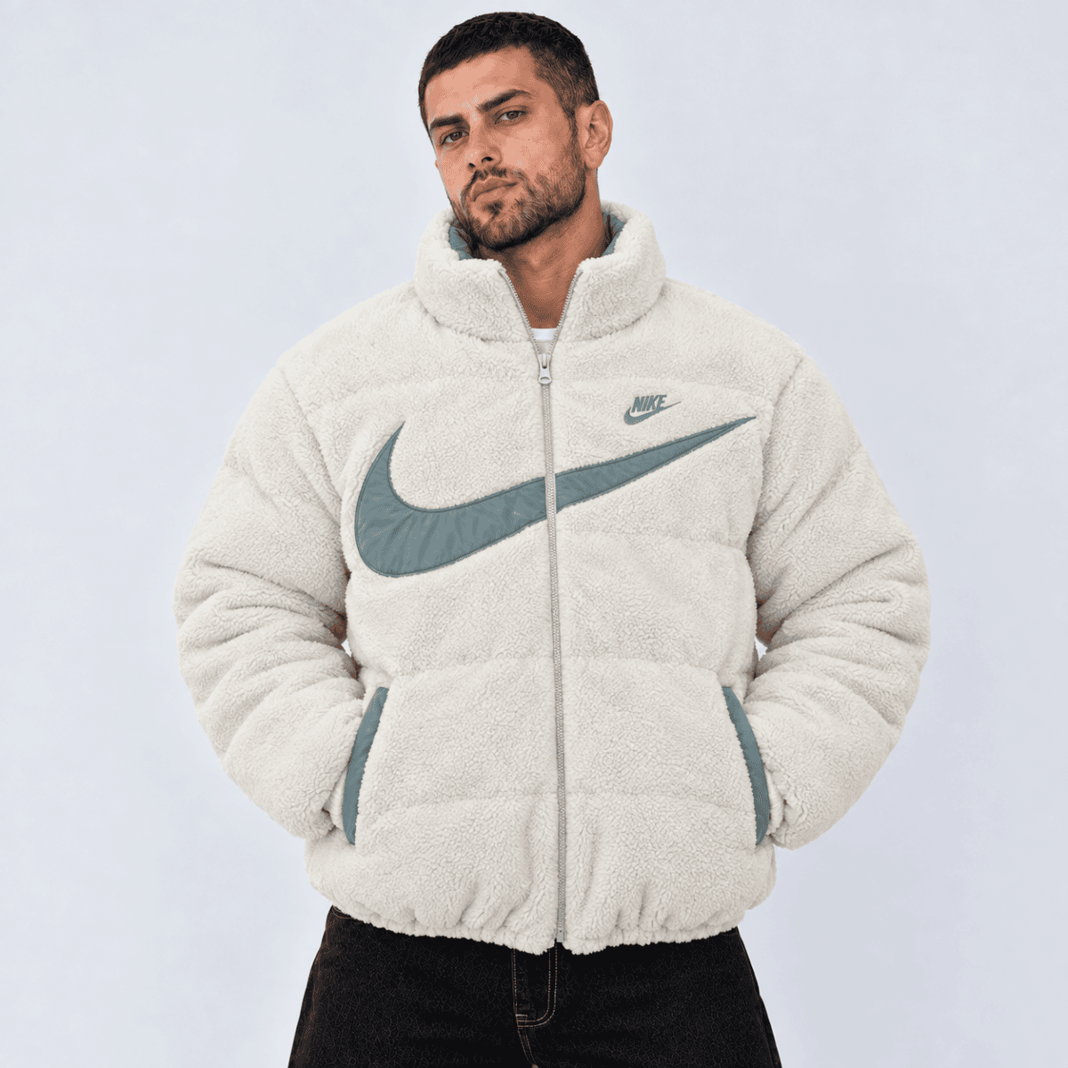 Man wearing a cream Nike fleece jacket with large gray swoosh logo.