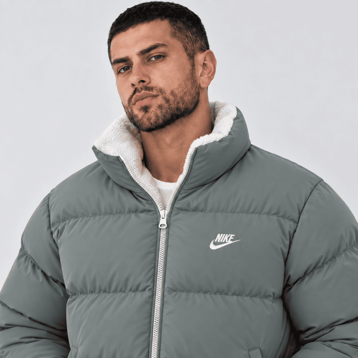 Man wearing a grey Nike puffer jacket with white fleece lining.