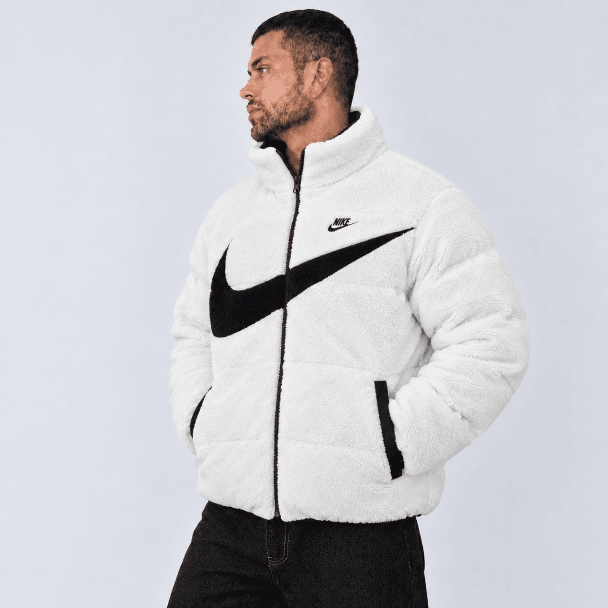 Man wearing a white Nike fleece jacket with black swoosh logo.