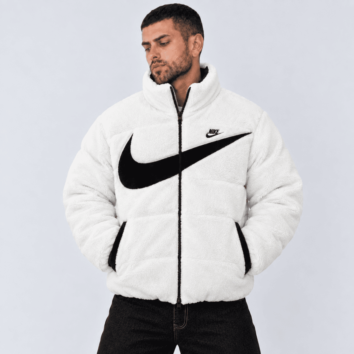 Man wearing white Nike fleece jacket with black swoosh logo.