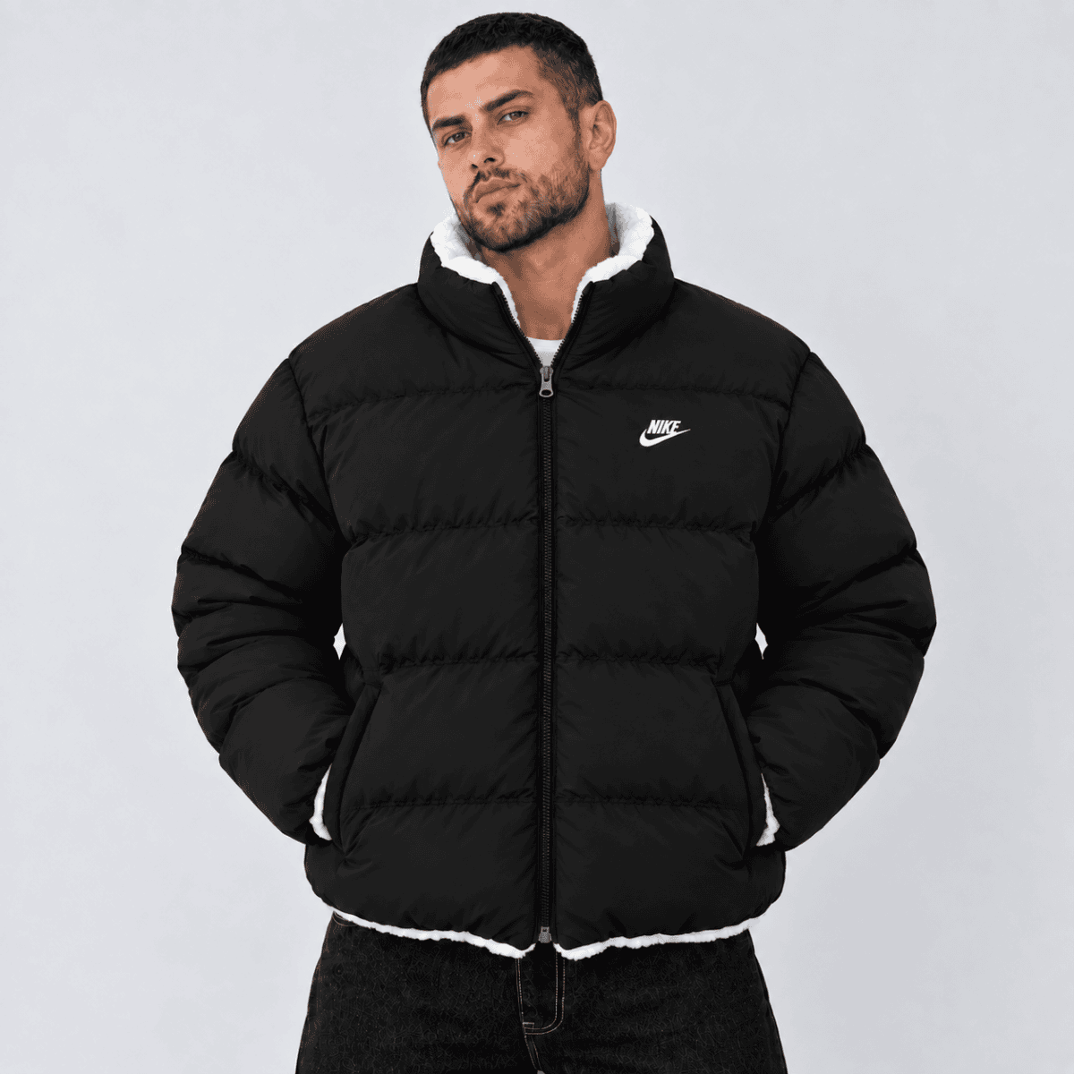 Man wearing black Nike puffer jacket with white logo and lining.