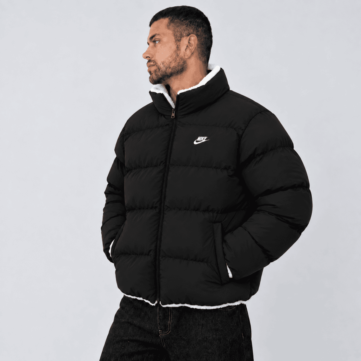 Black Nike puffer jacket with white logo and collar, front view.