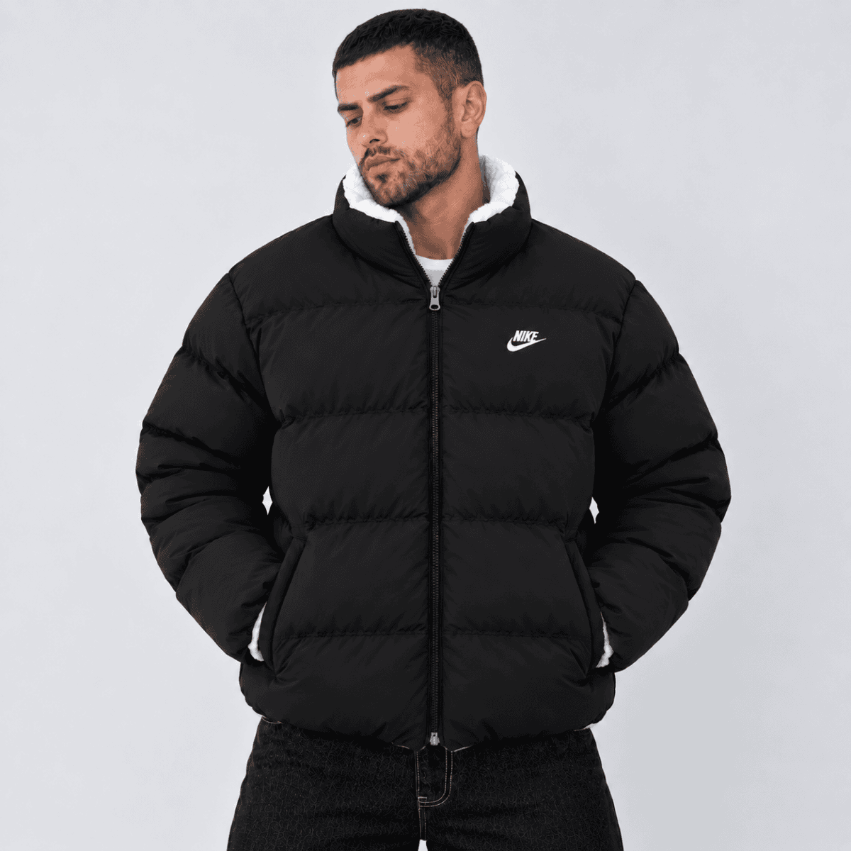 Man wearing black Nike puffer jacket with white logo and hood.