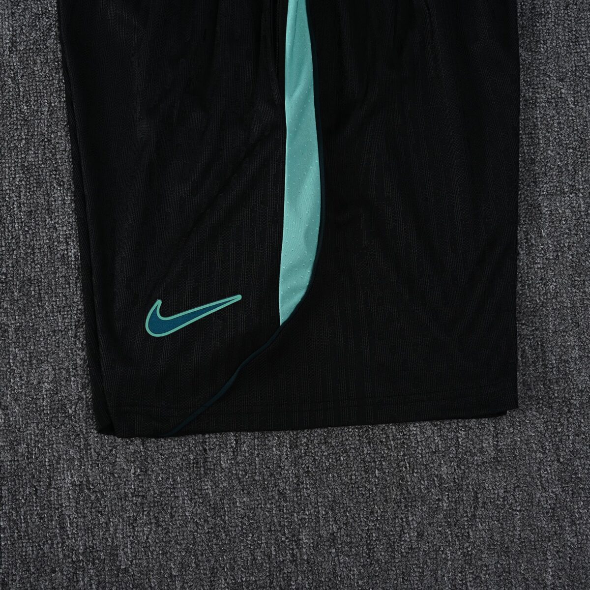 Close-up of black Nike sports shorts with light blue accents and logo.