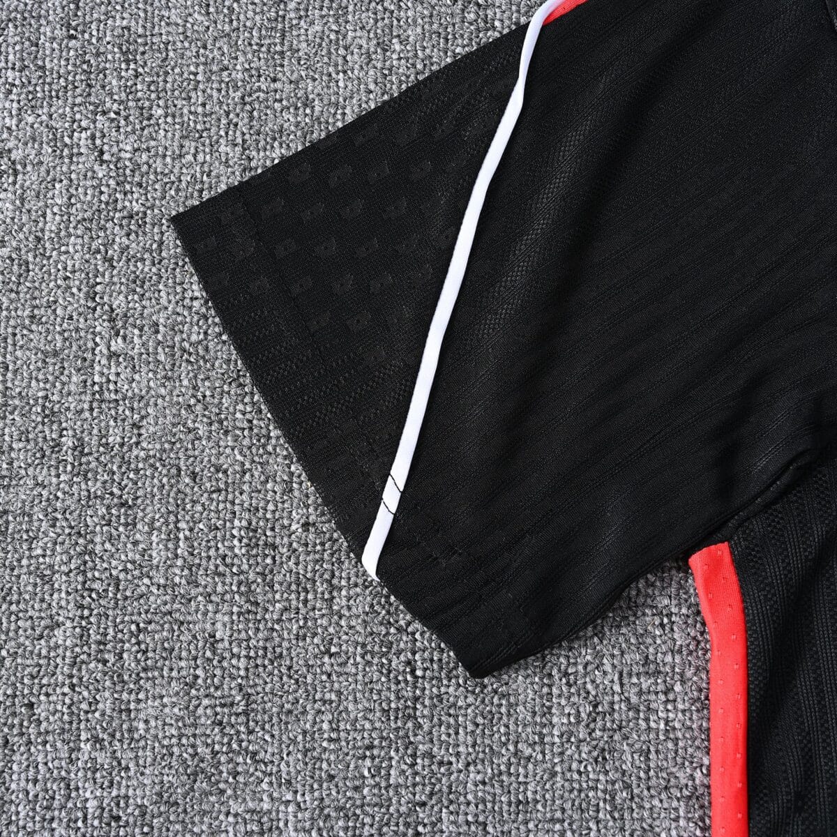 Close-up of black sports jersey with red and white accents on gray background.