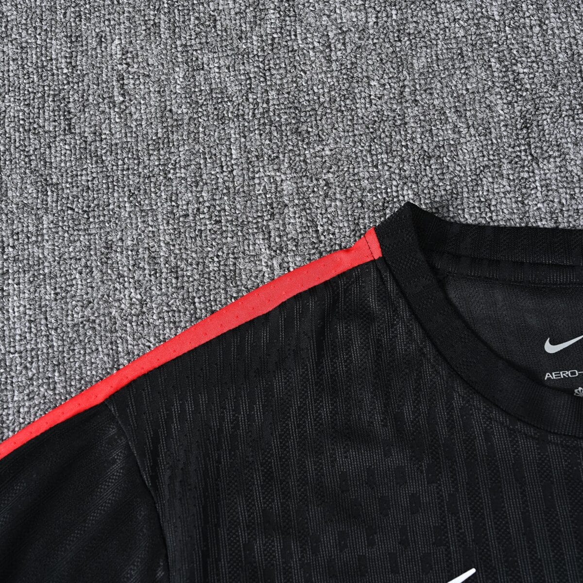 Close-up of black football jersey with red stripe and Nike logo.