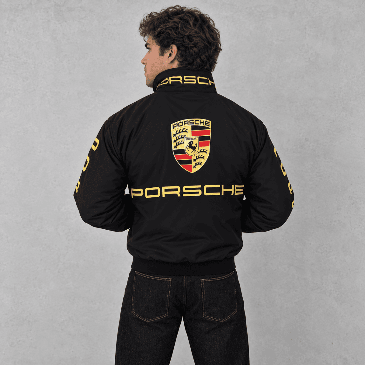 Porsche racing jacket with logo and yellow accents on black fabric.
