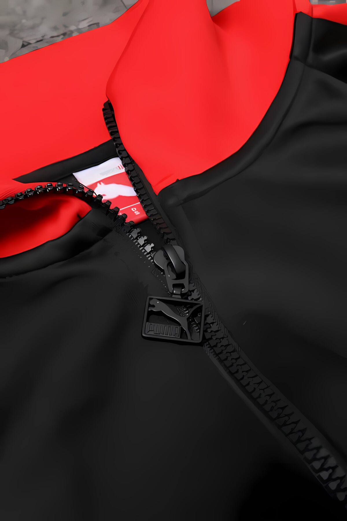 Close-up of black and red sports jacket with zipper and elastic detail.