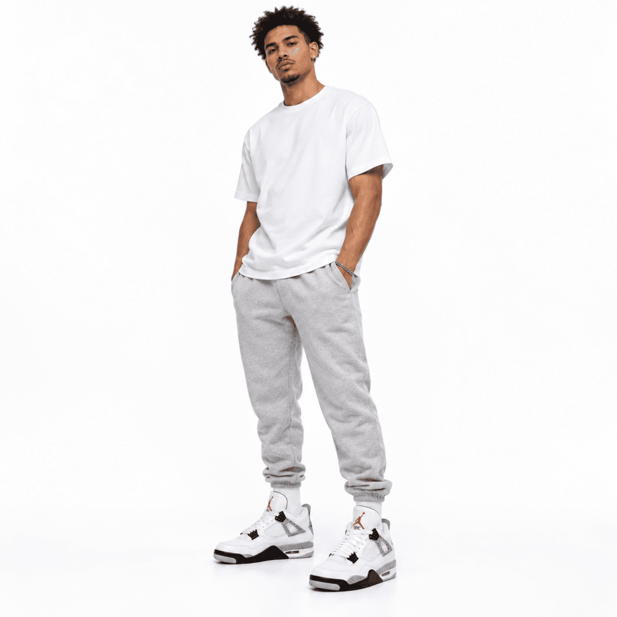 Man in white t-shirt, gray sweatpants, and white sneakers standing against white background.