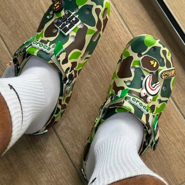 b887020c-160b-4794-a26f-5f037165d398 - UAE SPORT STORE BAPE x Crocs Classic Clog in ABC Camo Green on feet with white socks.