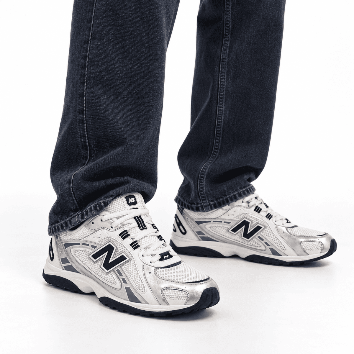 Person wearing New Balance 204L trainers in silver metallic and black with jeans.