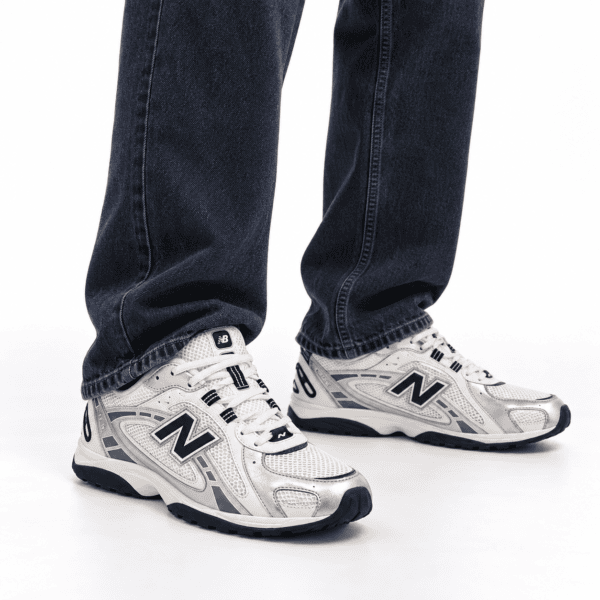 bcbd41be-d456-4825-9cca-e36cf0b283fc - UAE SPORT STORE Person wearing New Balance 204L trainers in silver metallic and black with jeans.