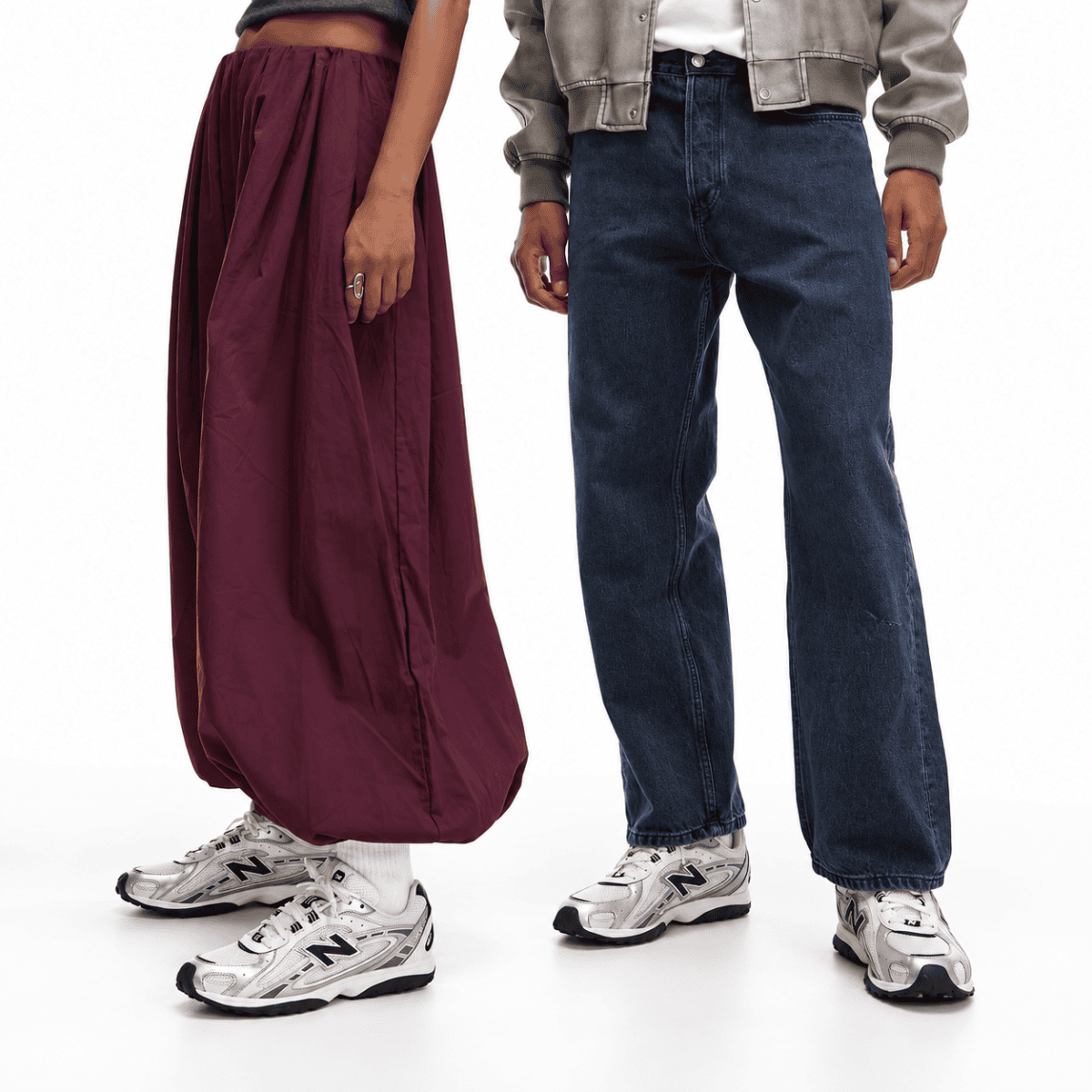 Two people wearing New Balance 204L trainers in silver metallic and black.