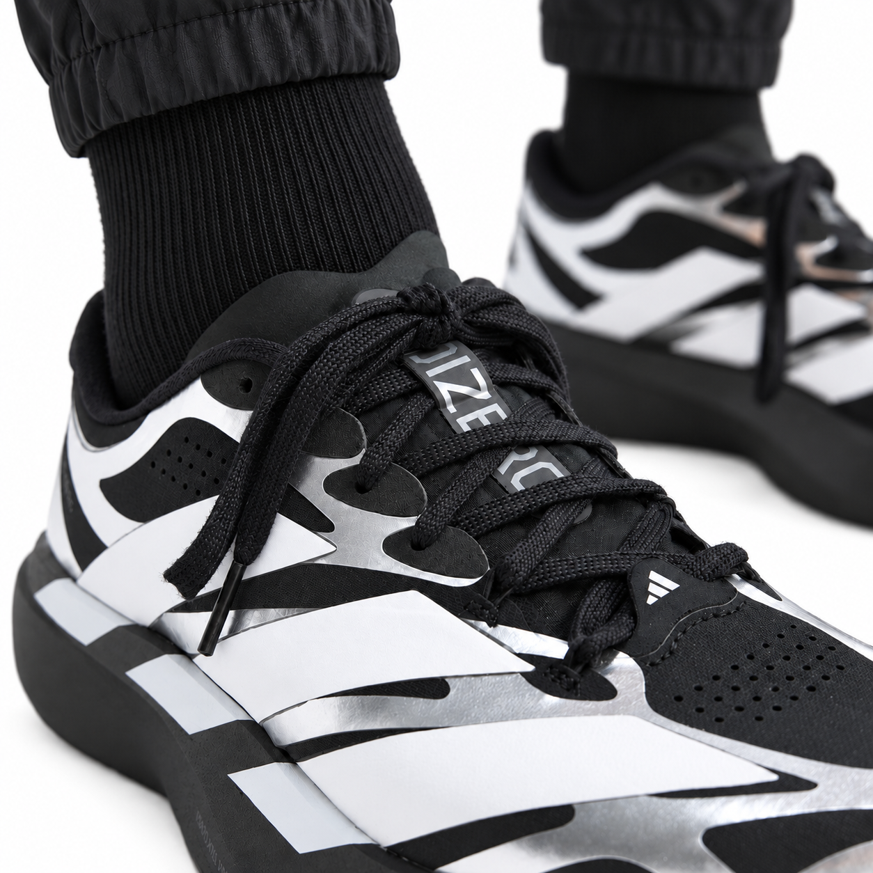 e4730de2-1bbb-4214-b875-7948231e7043 - UAE SPORT STORE Close-up of black and white adidas Adizero Evo SL EXO running shoes with laces.
