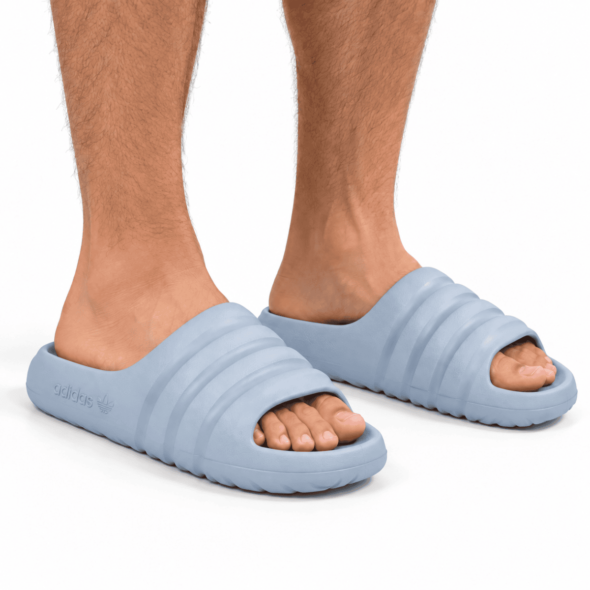 Light blue Adidas Adilette slides worn by a person with visible legs.