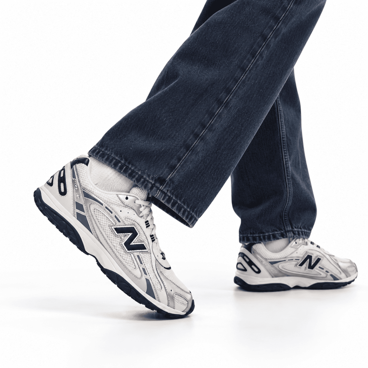 Person wearing New Balance 204L trainers in silver metallic and black with blue jeans.