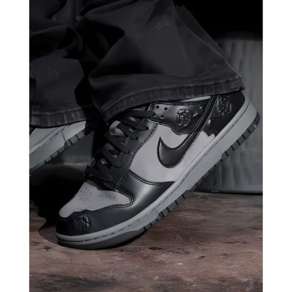 Black and white Nike sneakers on wooden floor with black pants.