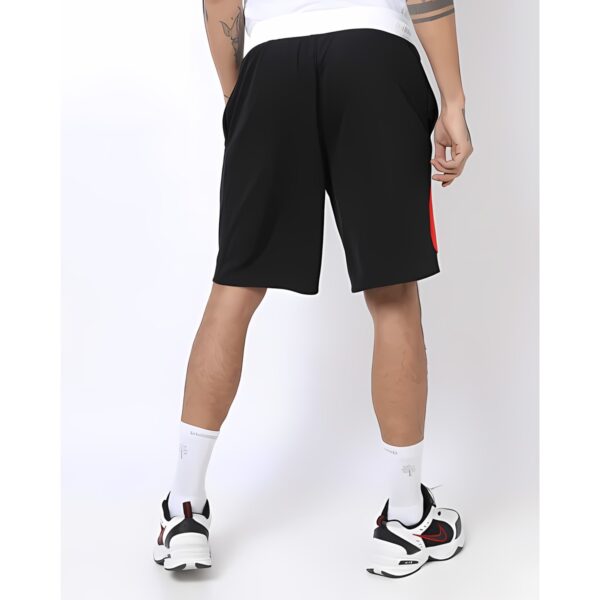 Man wearing black sports shorts, white socks, and Nike sneakers, back view.