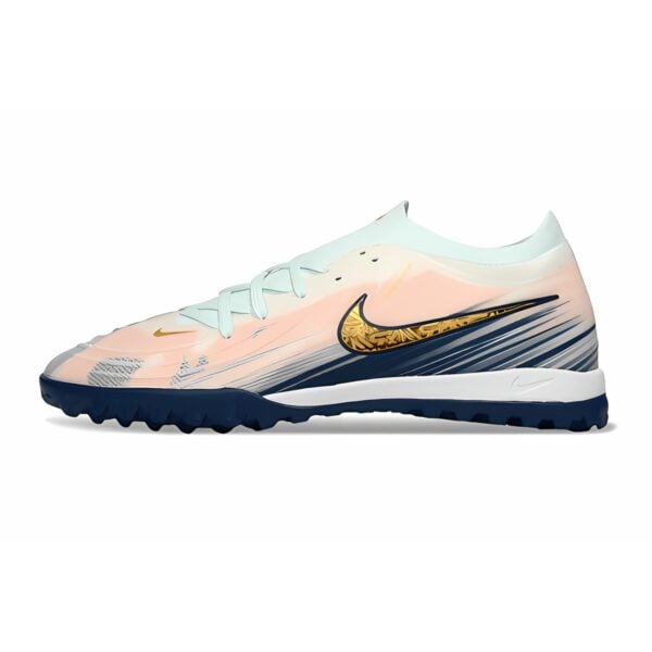 Nike football cleat with peach, white, and black colors and gold swoosh logo.