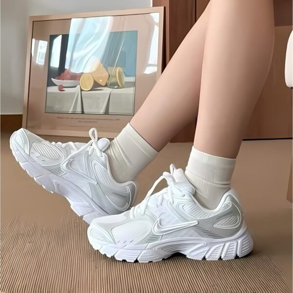 Person wearing white sneakers and socks sitting on the floor in front of a TV.