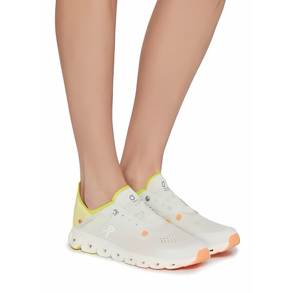 White and yellow sports shoes with orange accents on a person's feet.
