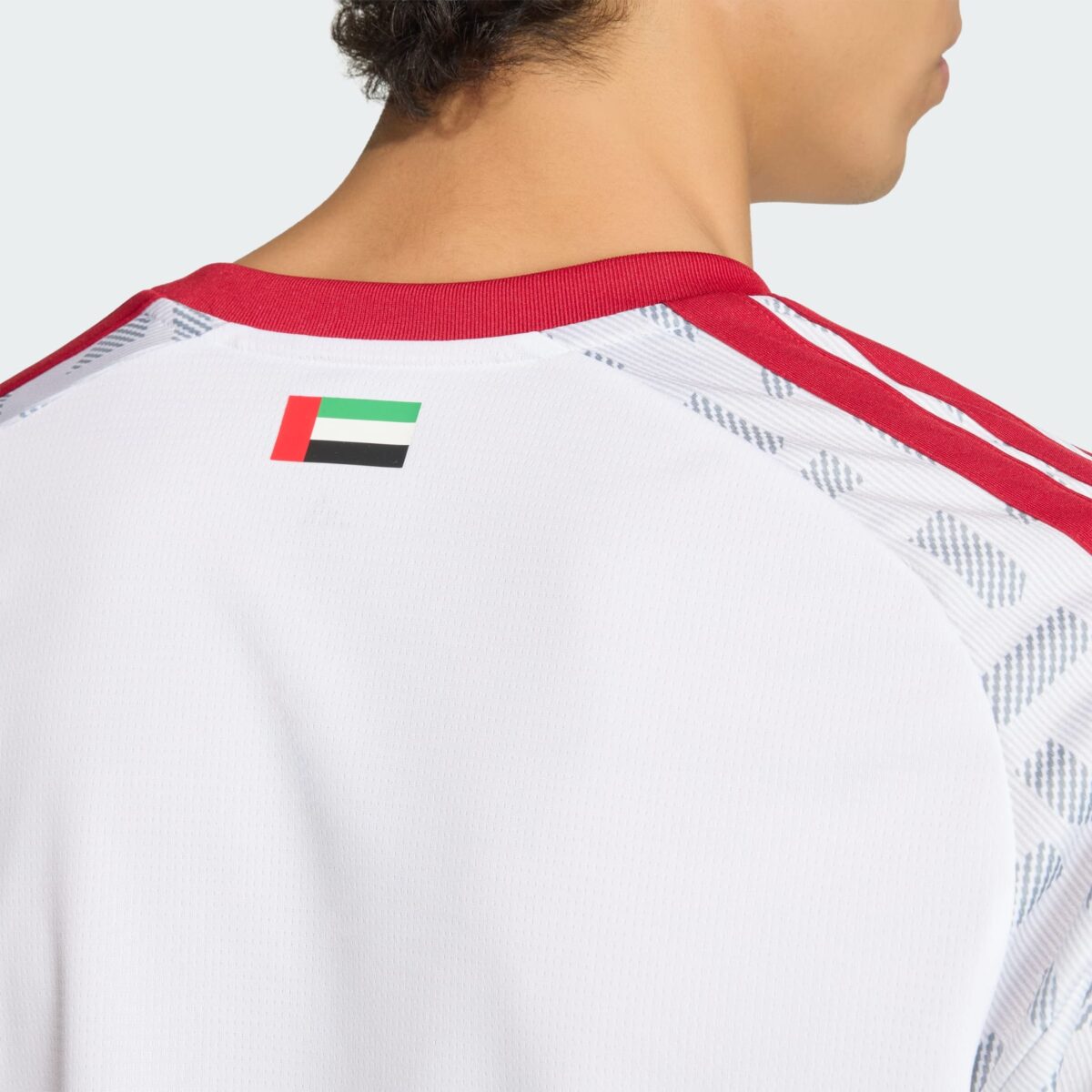 Close-up of a football jersey with UAE flag on the back, white with red accents.