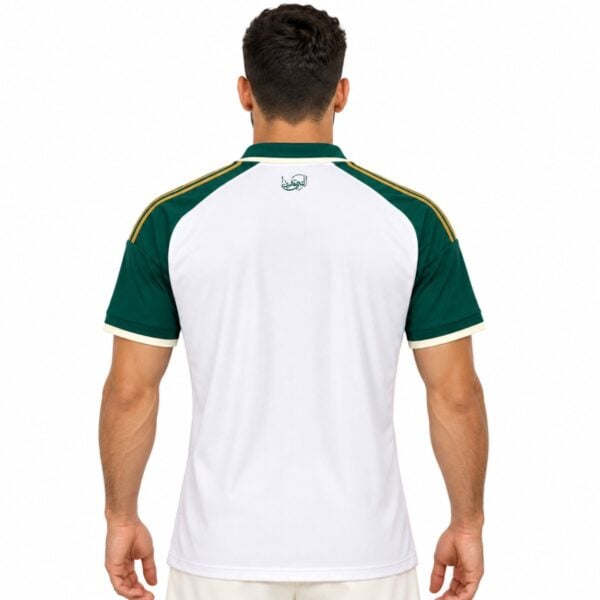 Rear of the white Al Ahli shirt with green shoulders, gold stripes and a small graphic below the collar.