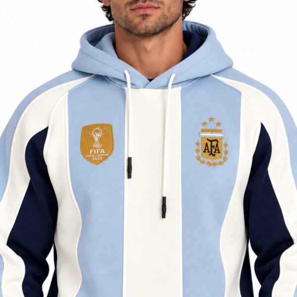 Argentina striped hoodie close-up showing embroidered AFA crest gold world champions badge and cream drawcords