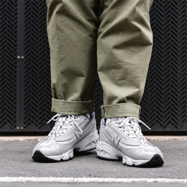 New Balance 1000 grey and white sneakers worn standing with olive trousers