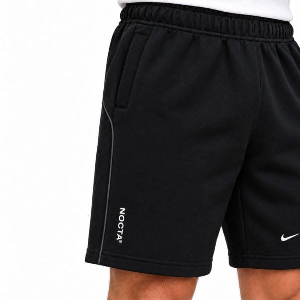 Black Nike sports shorts with white logo and NOCTA branding on the side.