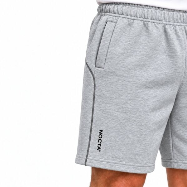 Grey sports shorts with black piping and NOCTA logo on the side.