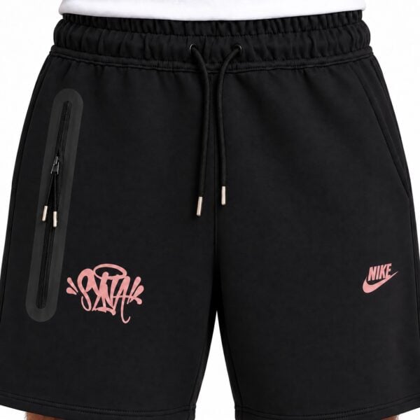 Black Nike sports shorts with pink logo and graffiti-style design.