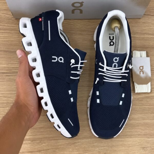 On Cloud 6 Midnight White pair held in hand showing the side and top with Swiss Engineering tab