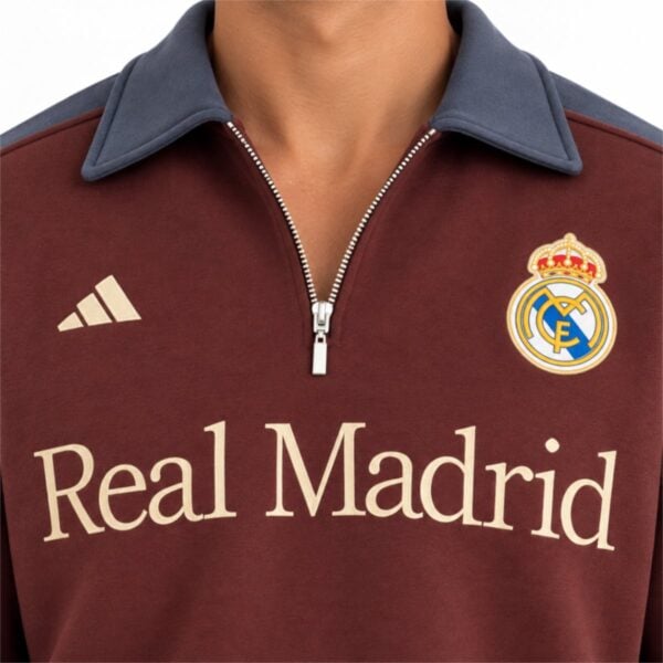 Real Madrid burgundy quarter zip close up of slate collar crest and sand wordmark